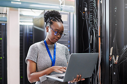 A young female Bachelor of Information Technology student standing and using a laptop (430x286)
