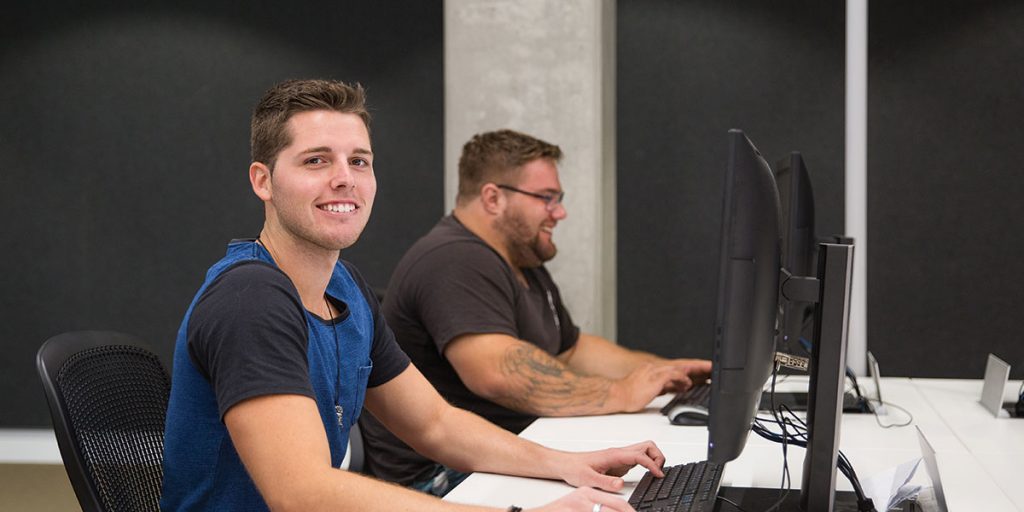Two young male students working at desktop computers, sitting in profile to camera - Certified Practising Accountant (CPA)