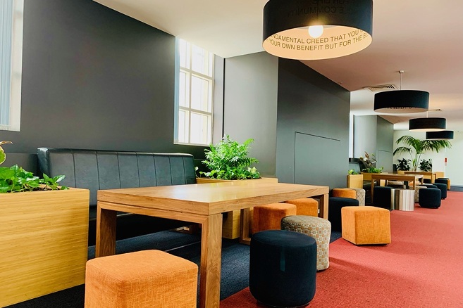 Common area at CSU Melbourne campus with long tables and padded chairs - 657x438