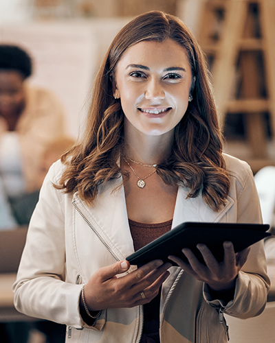 A female Graduate Certificate of Human Services student standing with a tablet in her hands and smiling towards camera (400x500).
