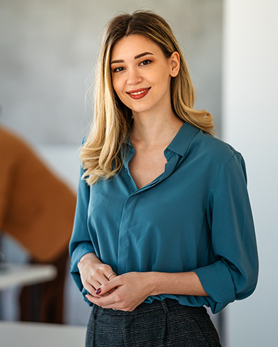 A female Master of Health Professional Practice student standing in an office space, smiling towards camera (400x500)