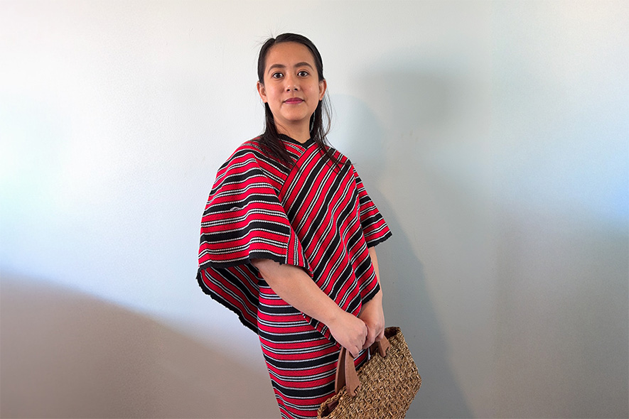 Master of Professional Accounting (Professional Practice) student Nissan wearing a kimona and holding a woven handbag in front of a white wall (885x590)