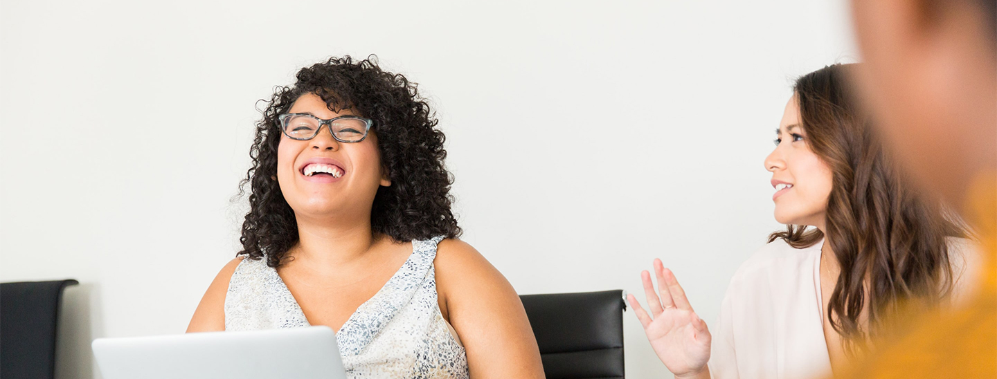 Two women desk laptop laughing smiling