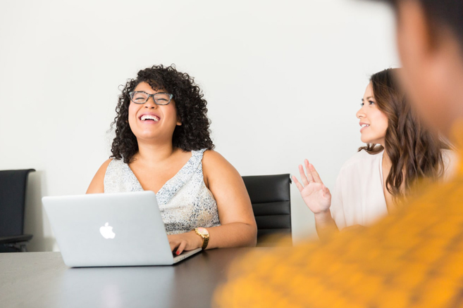 Two women laptop desk smiling laughing